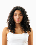 Woman with full, defined curly hair showcasing volumizing results from Decibel thickening hair care.