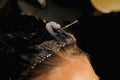 Stylist spraying Hypertrophy thickening treatment onto wet hair at the roots in a salon.